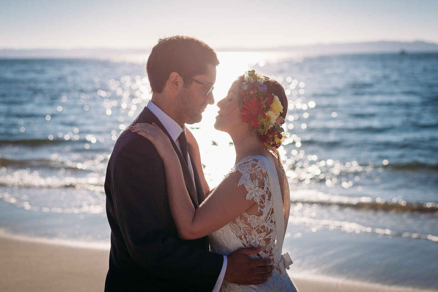 Novios abrazados en la playa a contraluz
